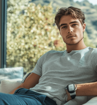 Un jeune homme mesurant sa tension avec le Braun ExactFit 3 Tensiomètre de bras dans son salon moderne, avec une grande baie vitrée en arrière-plan.